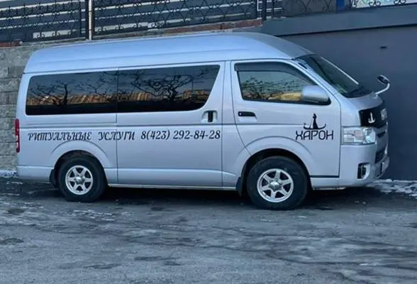 Серебристый микроавтобус Hiace с символикой «Харона», вид сбоку